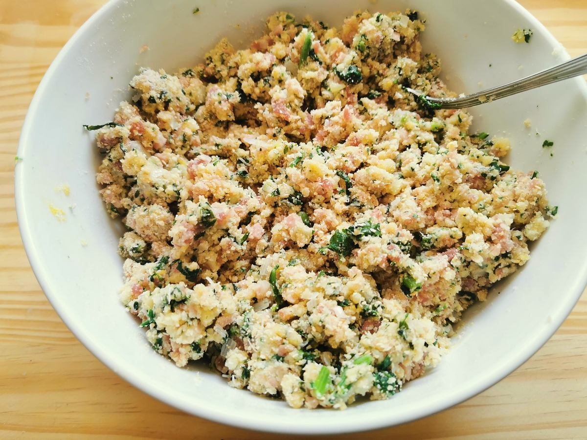 Casoncelli filling ingredients mixed together in white bowl.