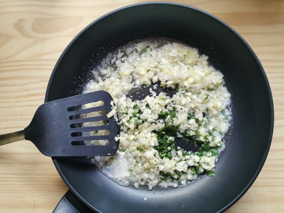 Chopped leeks and parsley in frying pan.