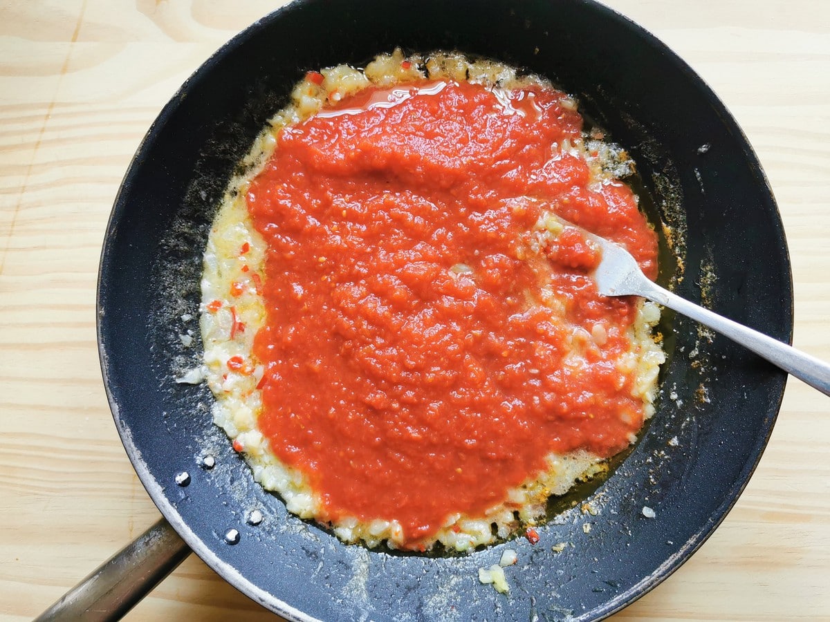 Tomato passata in skillet with cooked aglione (elephant garlic) and peperoncino.