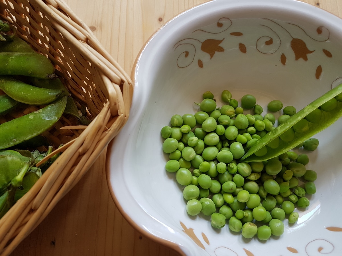 Fresh peas in white bowl.