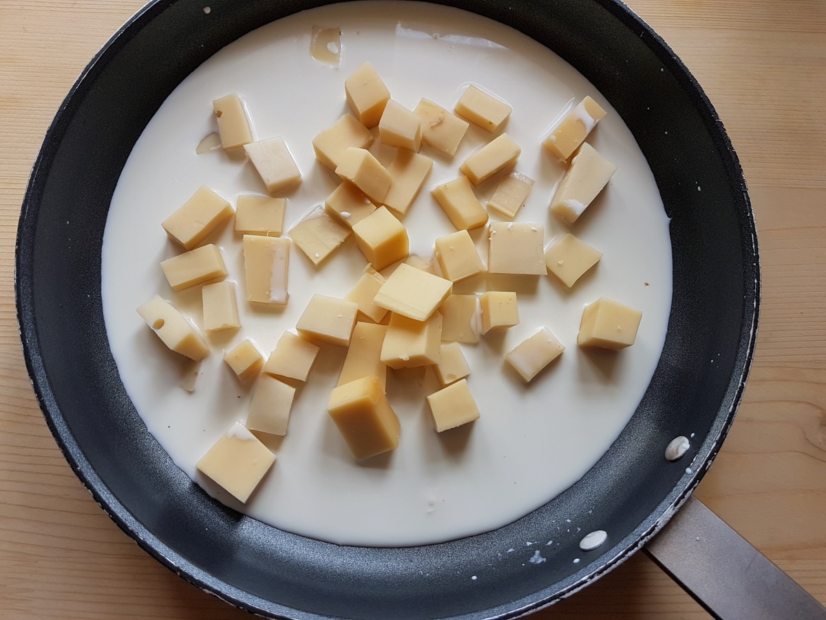 Fontina cheese with the milk and cream in a pan.