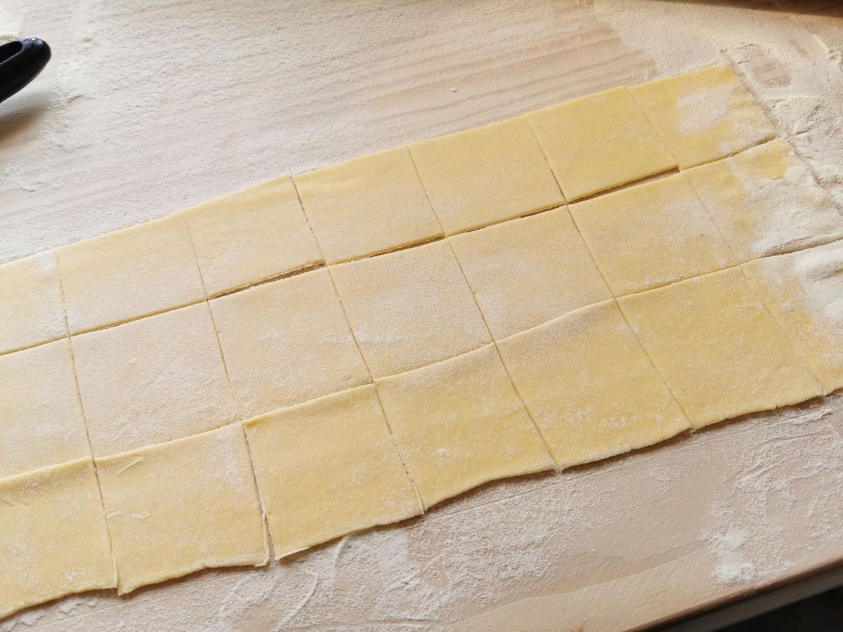 Sheet of pasta dough cut into squares.