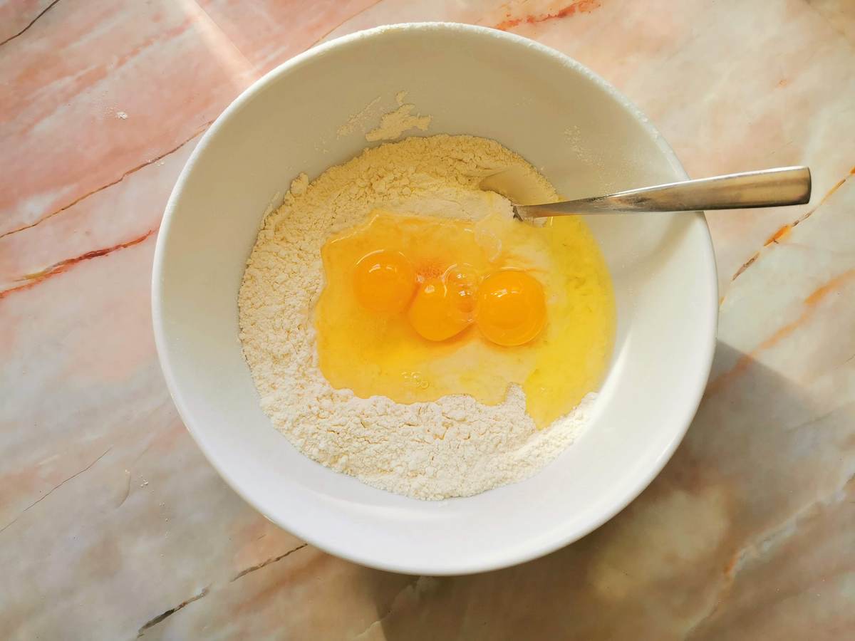 3 eggs broken into bowl with flour.