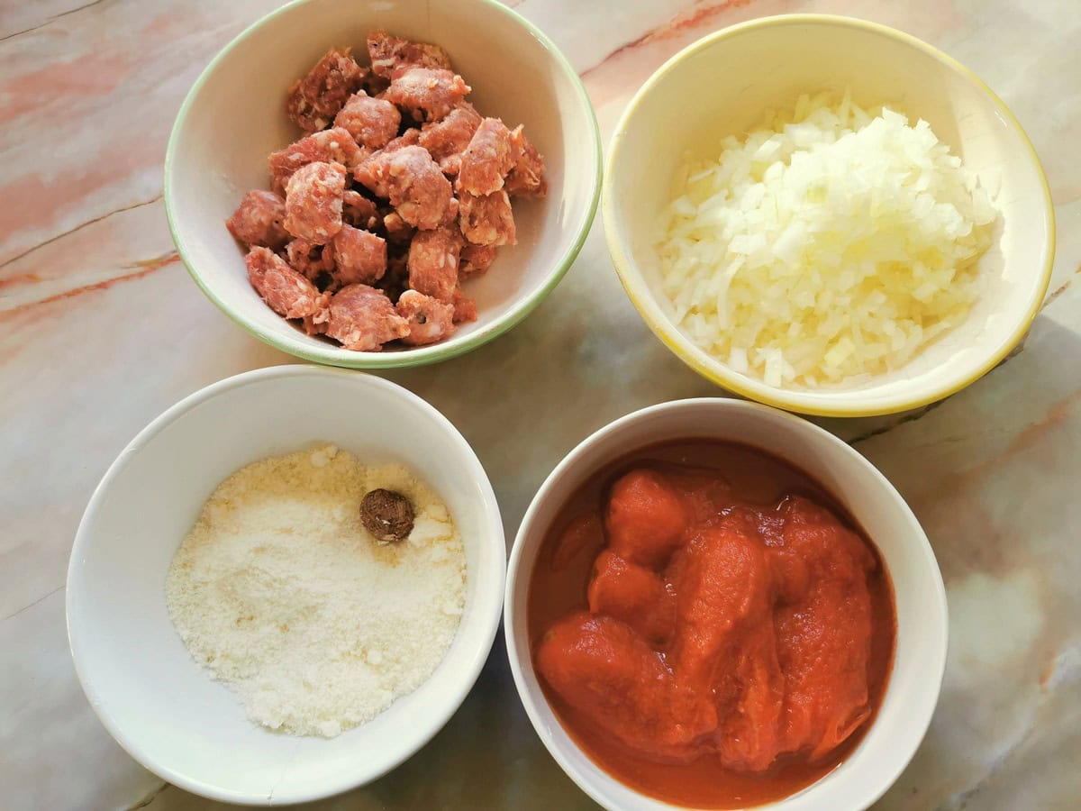 Prepared ingredients for sausage ragu in white bowls