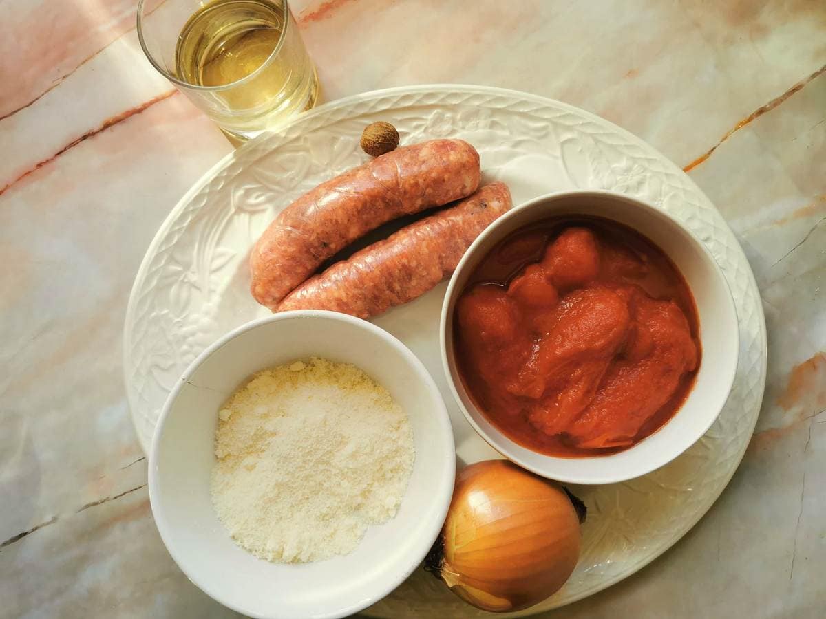 Ingredients for sasuage ragu; sausages, onion, canned tomatoes, wine and nutmeg.