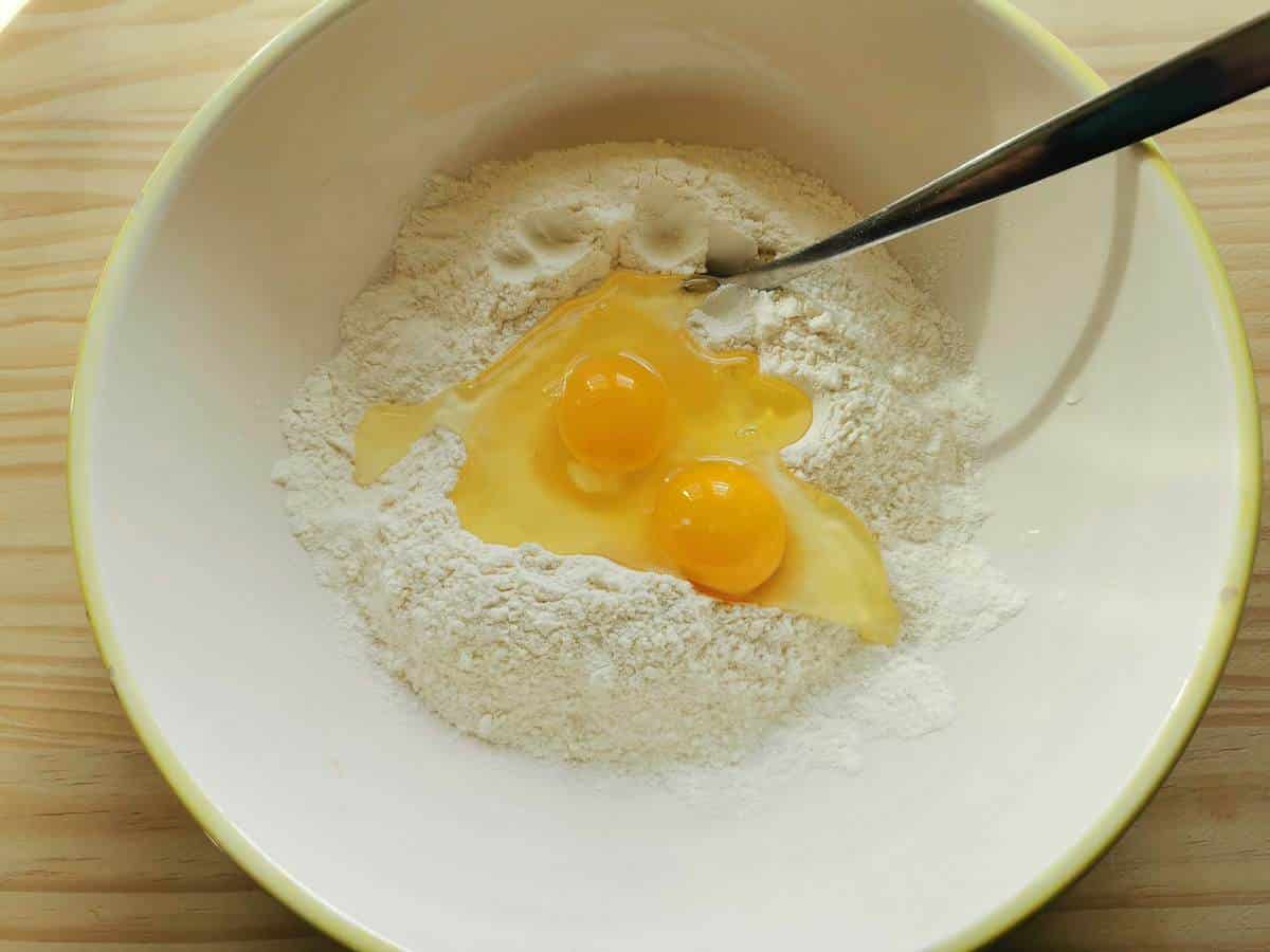 Italian '00' flour in white bowl with 2 eggs.