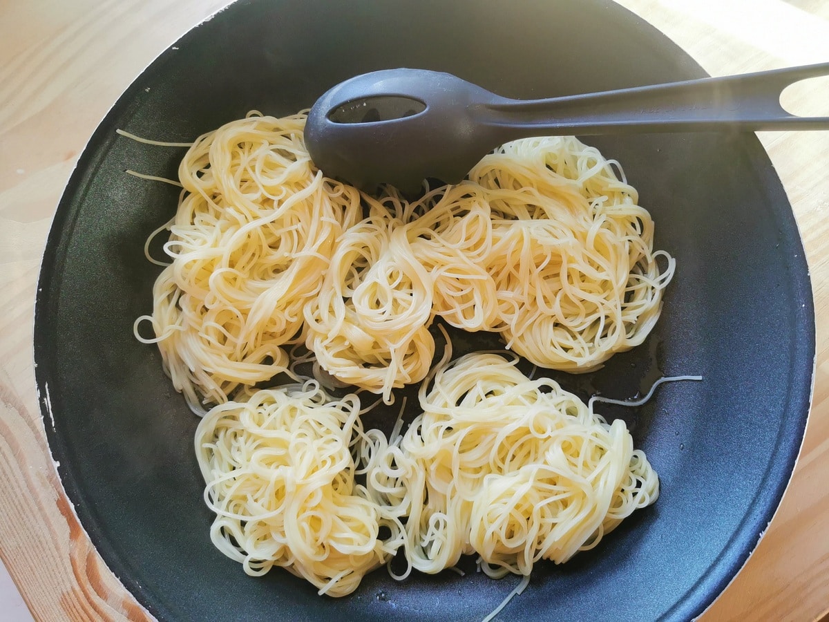 Cooked angel hair pasta in small frying pan.