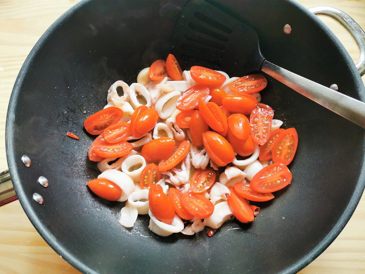 Halved tomatoes added to the pan.