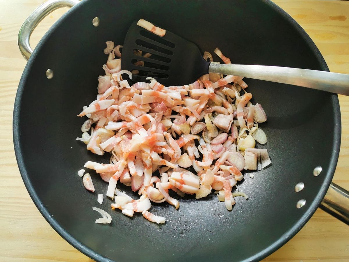 Shallots and guanciale in deep frying pan.