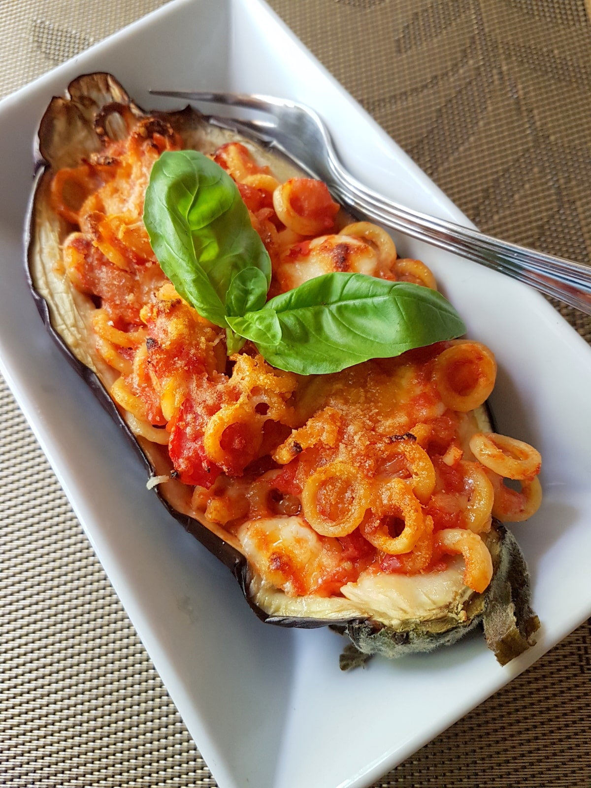 Eggplant boat with pasta, tomato and basil.