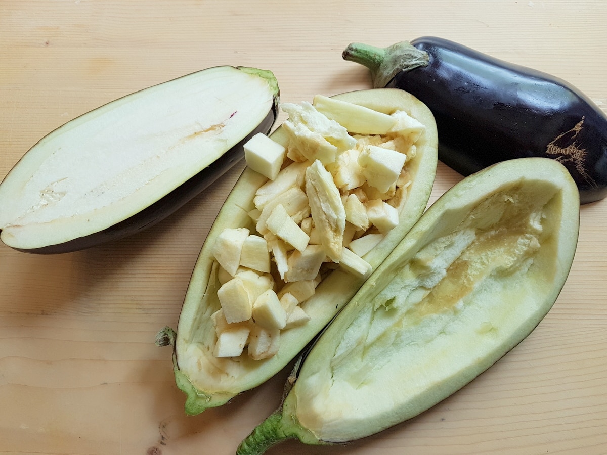 Eggplants that have been hollowed on a wooden board.