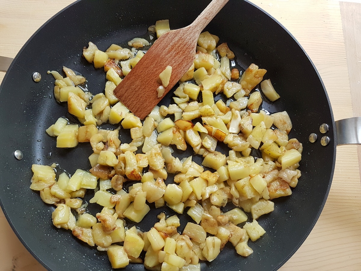 Cubed eggplant and garlic cooking in a pan.