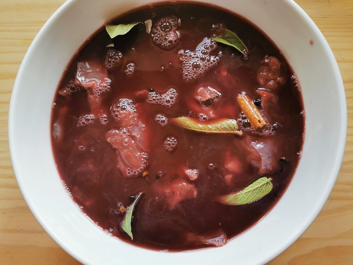 White bowl with red wine and hare meat inside.