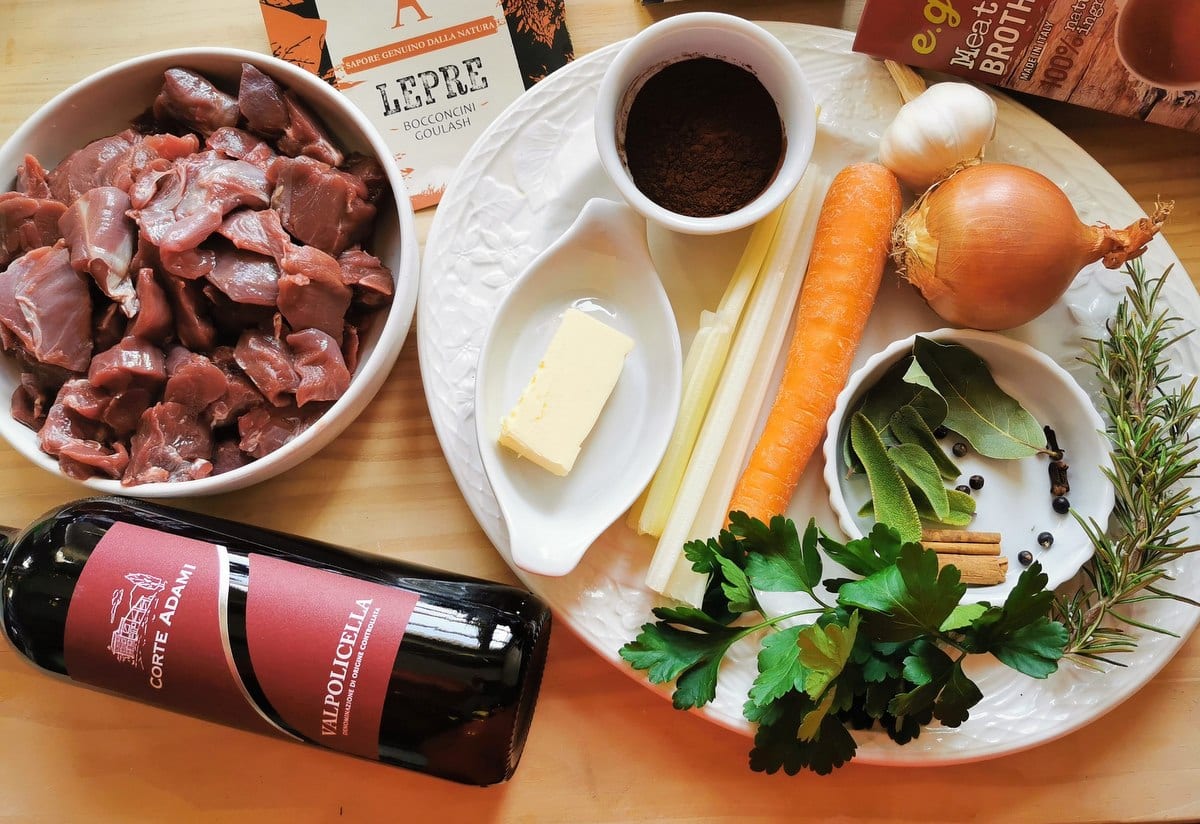 Ingredients for braised hare ragu on wood worktop.