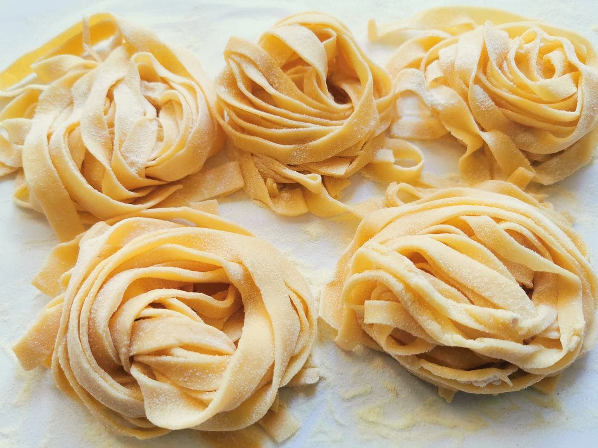 5 homemade tagliatelle pasta nests on kitchen (parchment) paper.