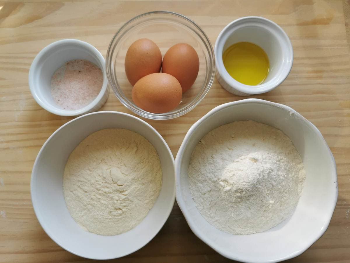 Ingredients for homemade tagliatelle pasta; eggs, soft wheat flour, hard wheat flour, salt and olive oil.