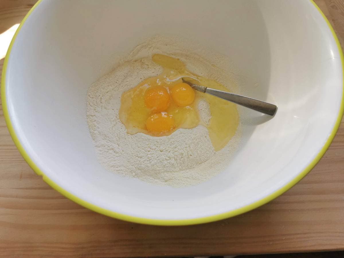 3 eggs broken into flour in a large bowl.