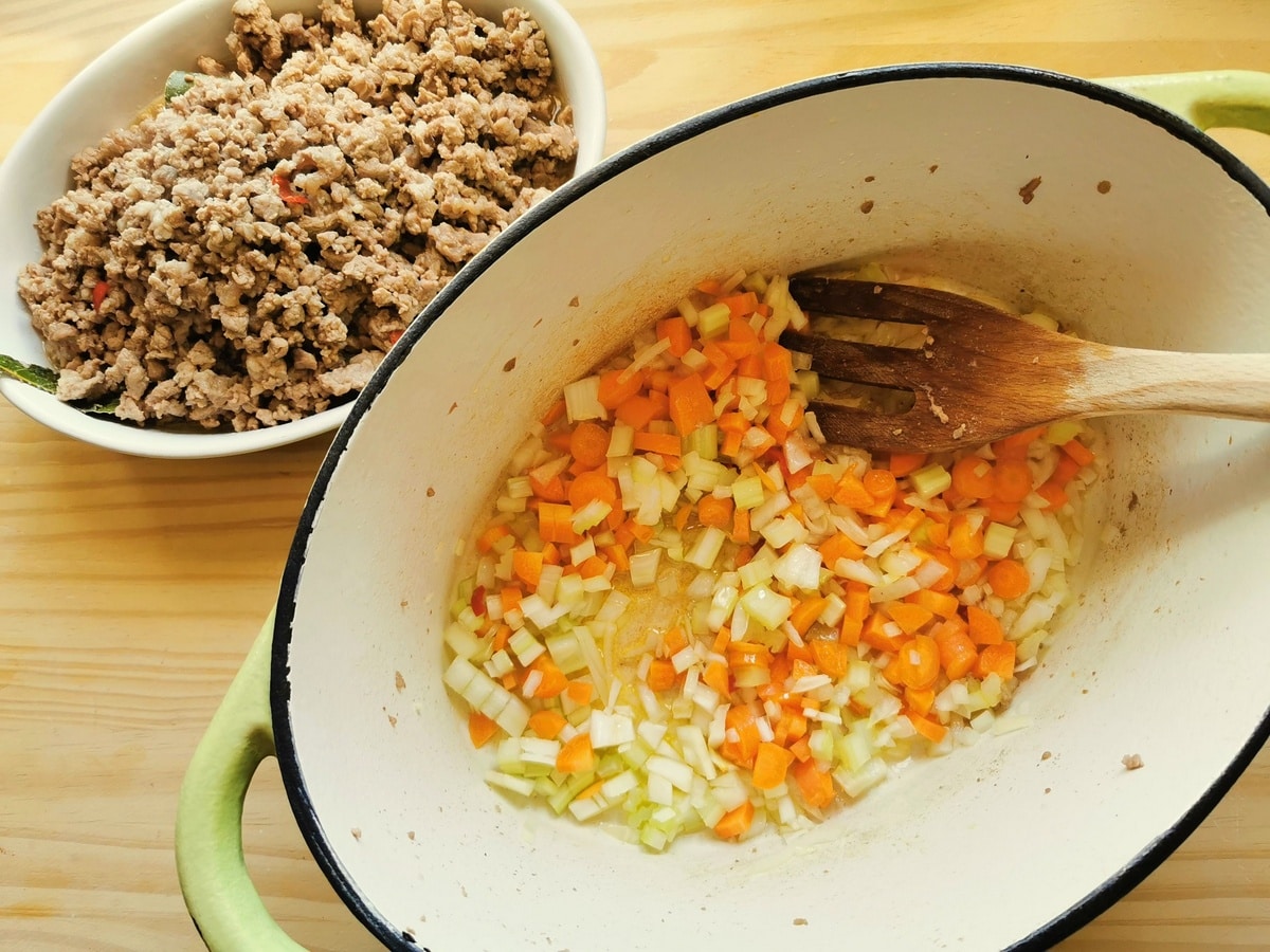 Chopped onions, carrots and celery in a pot.