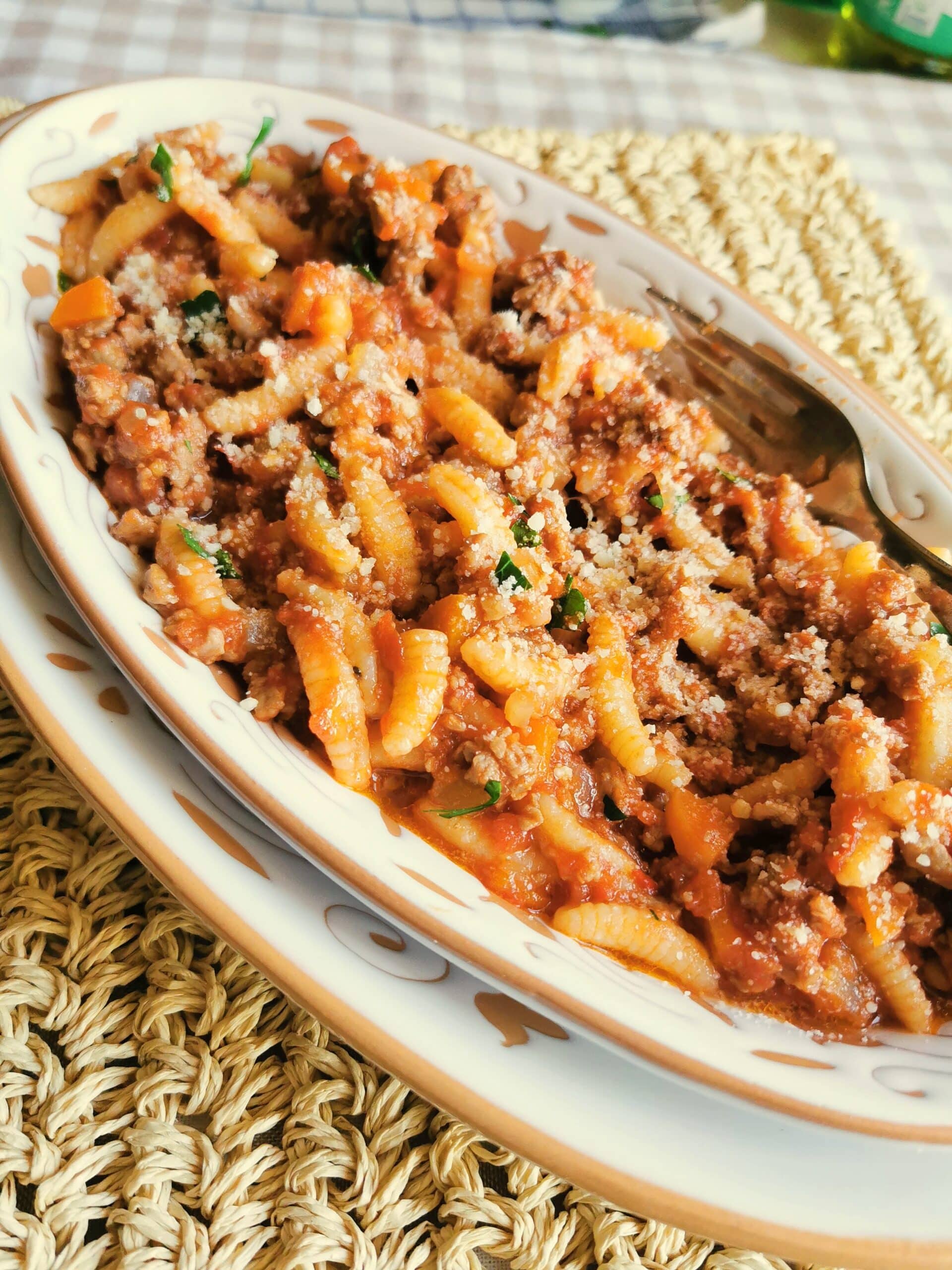 Grated Pecorino sprinkled over a plate of lamb ragu pasta.