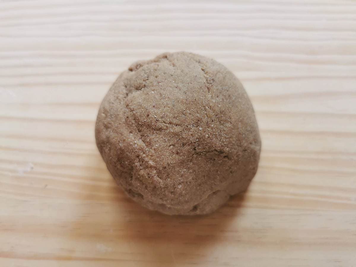 Ball of ready chestnut pasta dough on wood work surface.