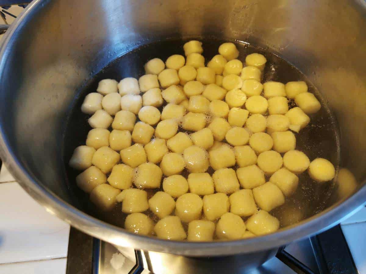 Potato gnocchi cooking in boiling salted water in large pot.