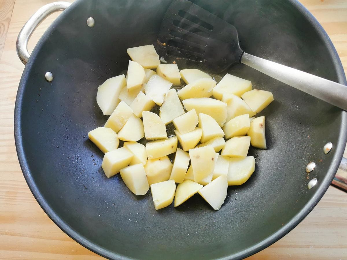 Cubed potatoes cooking in a pan.