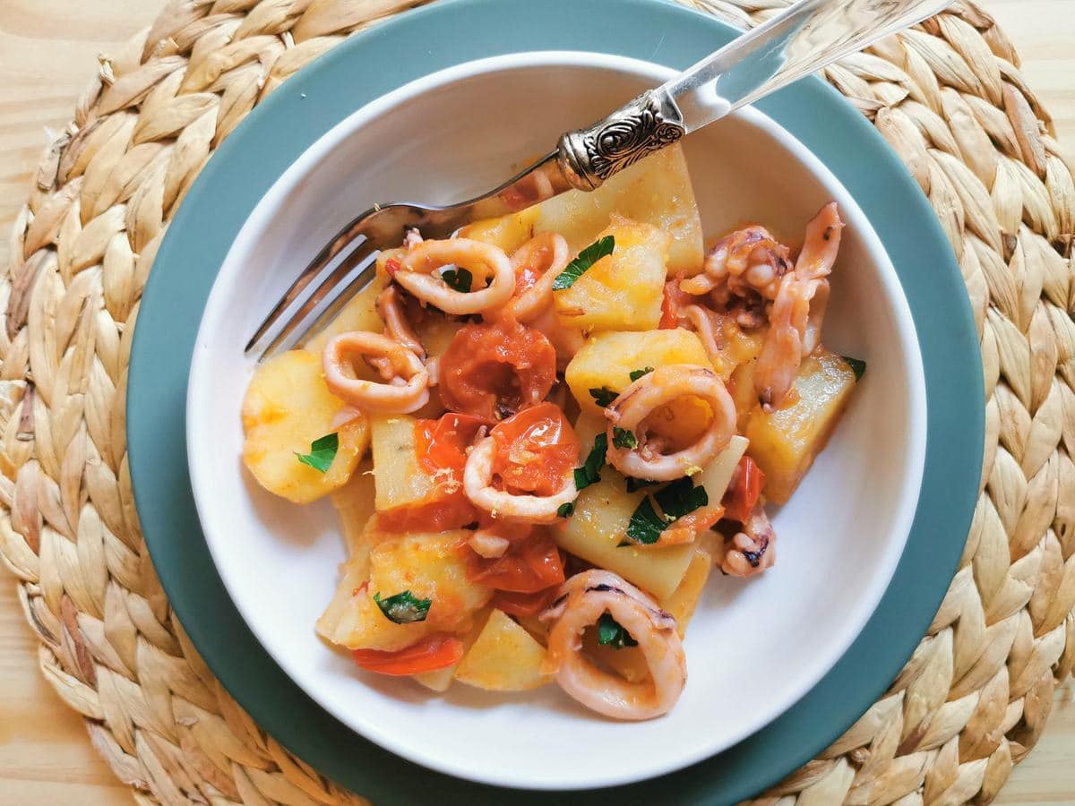 Paccheri pasta with calamari (squid) and potatoes in a white bowl.