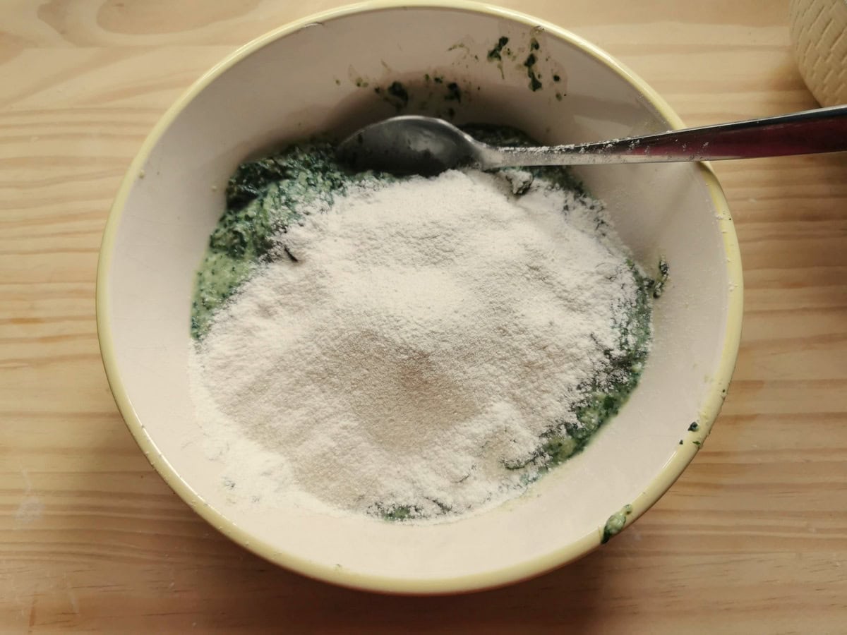 Soft wheat flour added to a white bowl in which there's the stangolapreti mixture.