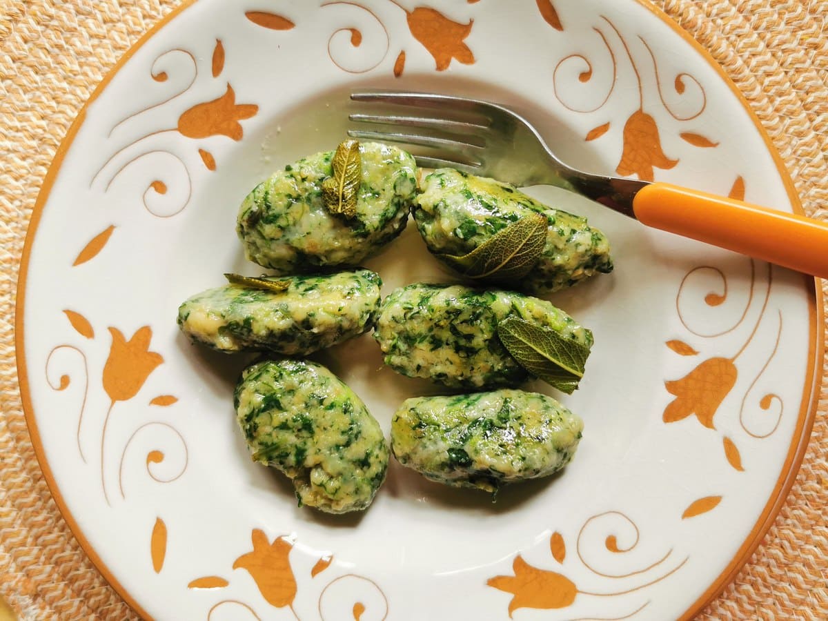 Strangolapreti gnocchi from Lombardy in white and orange bowl.