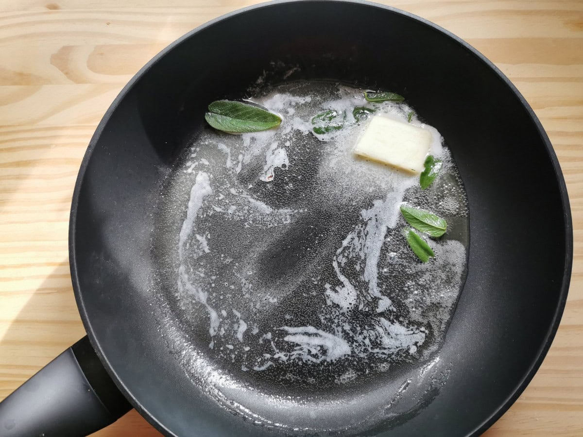 Butter and sage leaves in a frying pan.